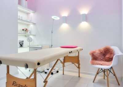 Interior of contemporary workplace of cosmetology salon with couch placed near armchair and shelves with cosmetic products